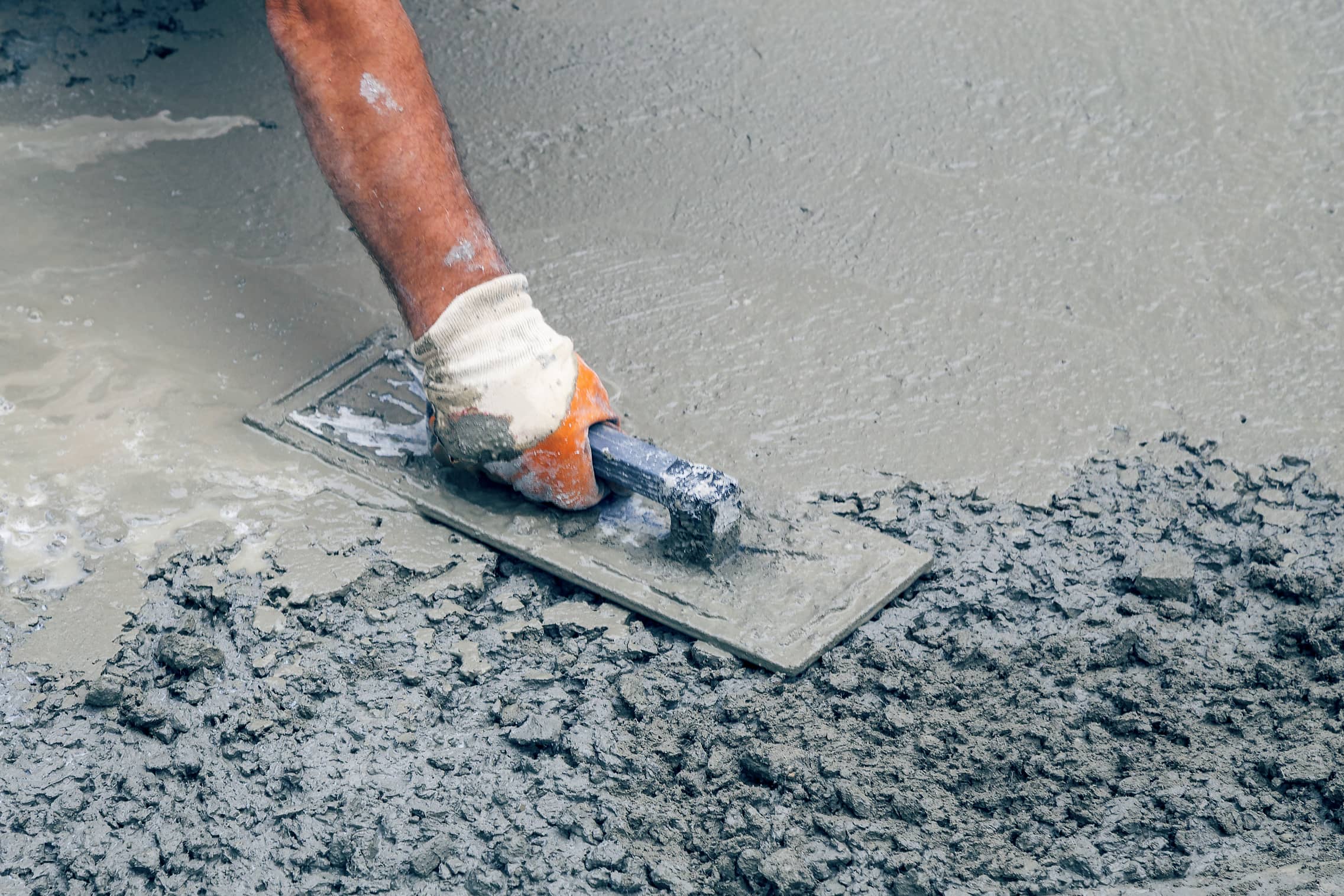 This is an image of a contractor smoothing out wet concrete with a trowel.